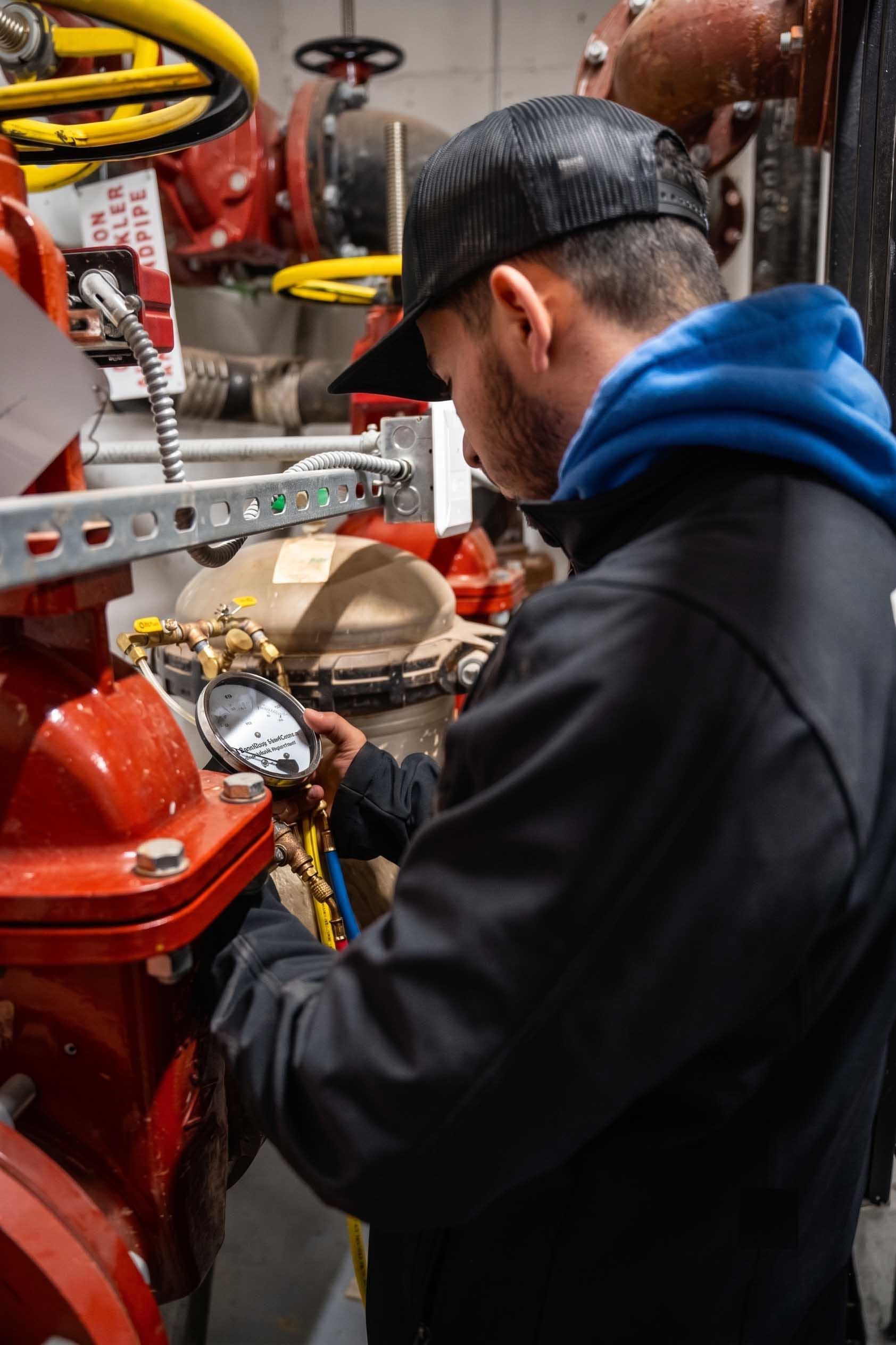 County Fire technician checking a fire sprinkler system pressure gauge during a repair