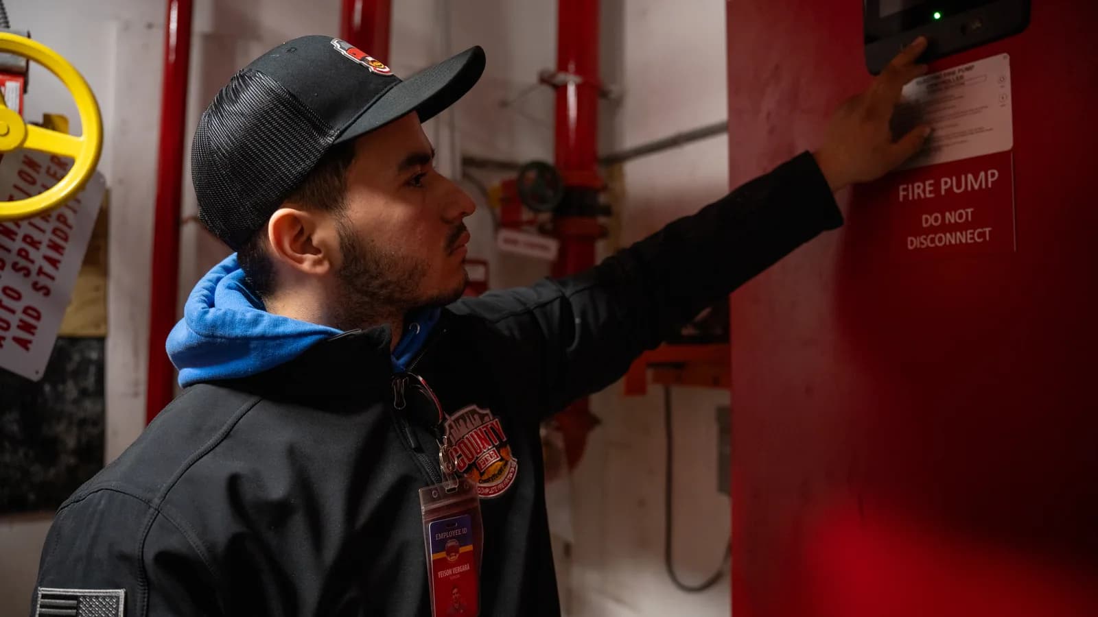 A County Fire technician checking an electric fire pump controller in a commercial building pump room