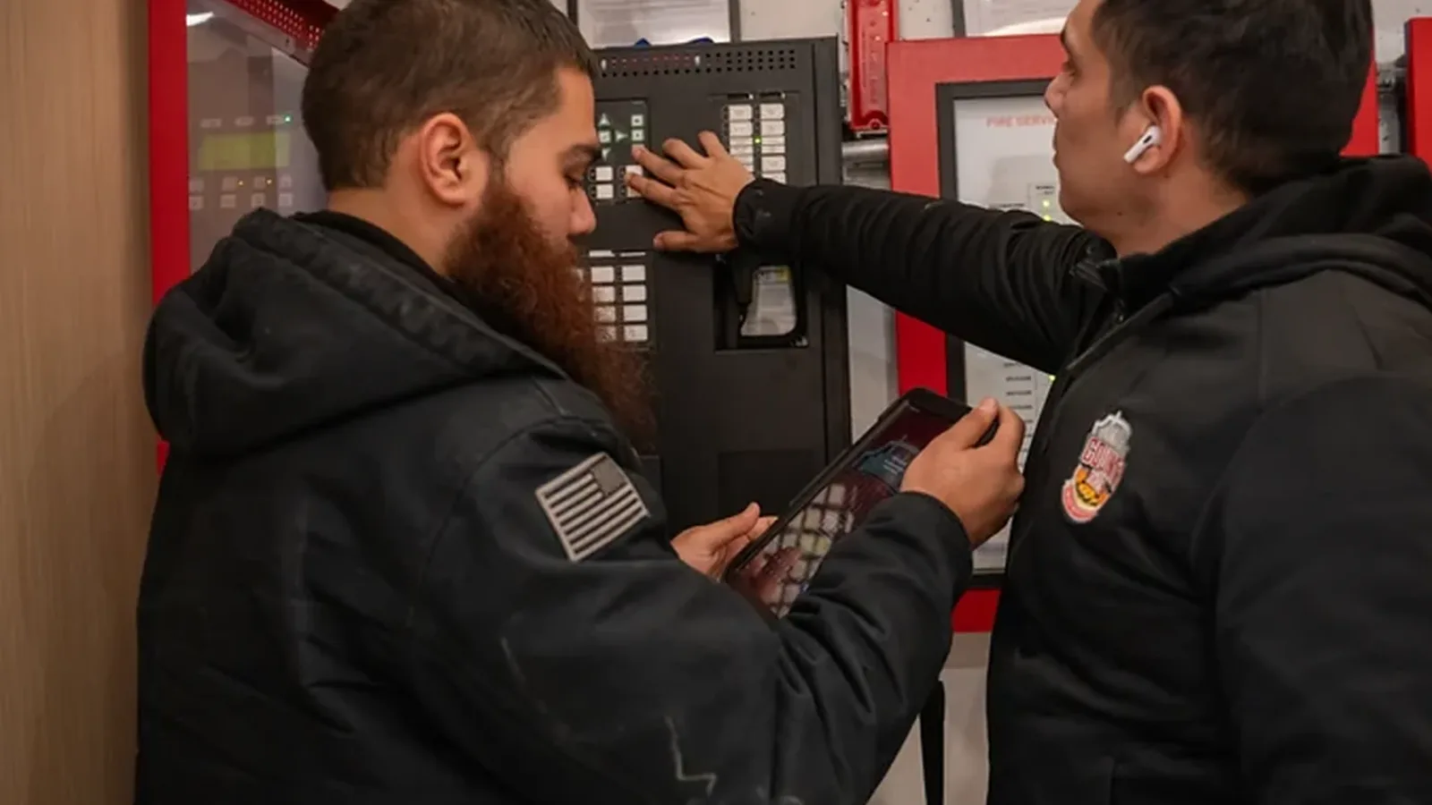 Two County Fire technicians inspecting a commercial fire alarm control panel