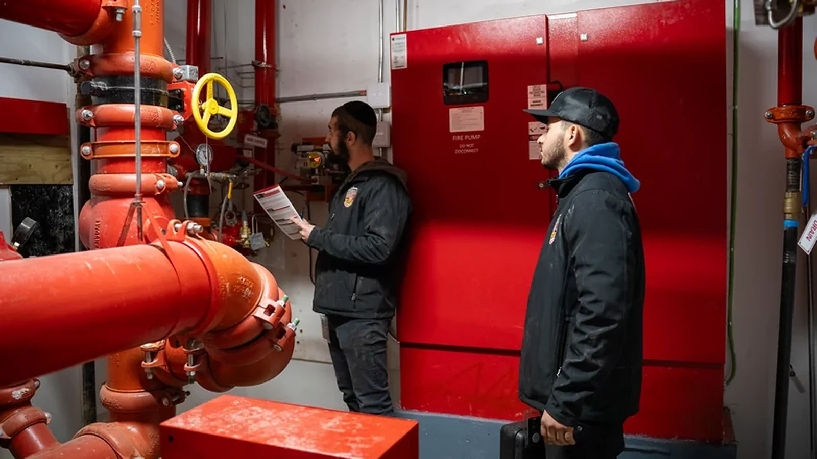 Two County Fire technicians reviewing records in a commercial fire pump room