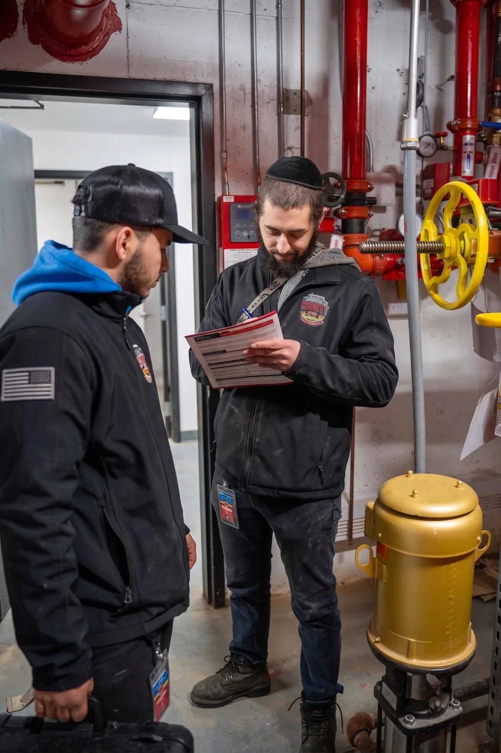 County Fire technicians reviewing an inspection report in a Staten Island fire pump room