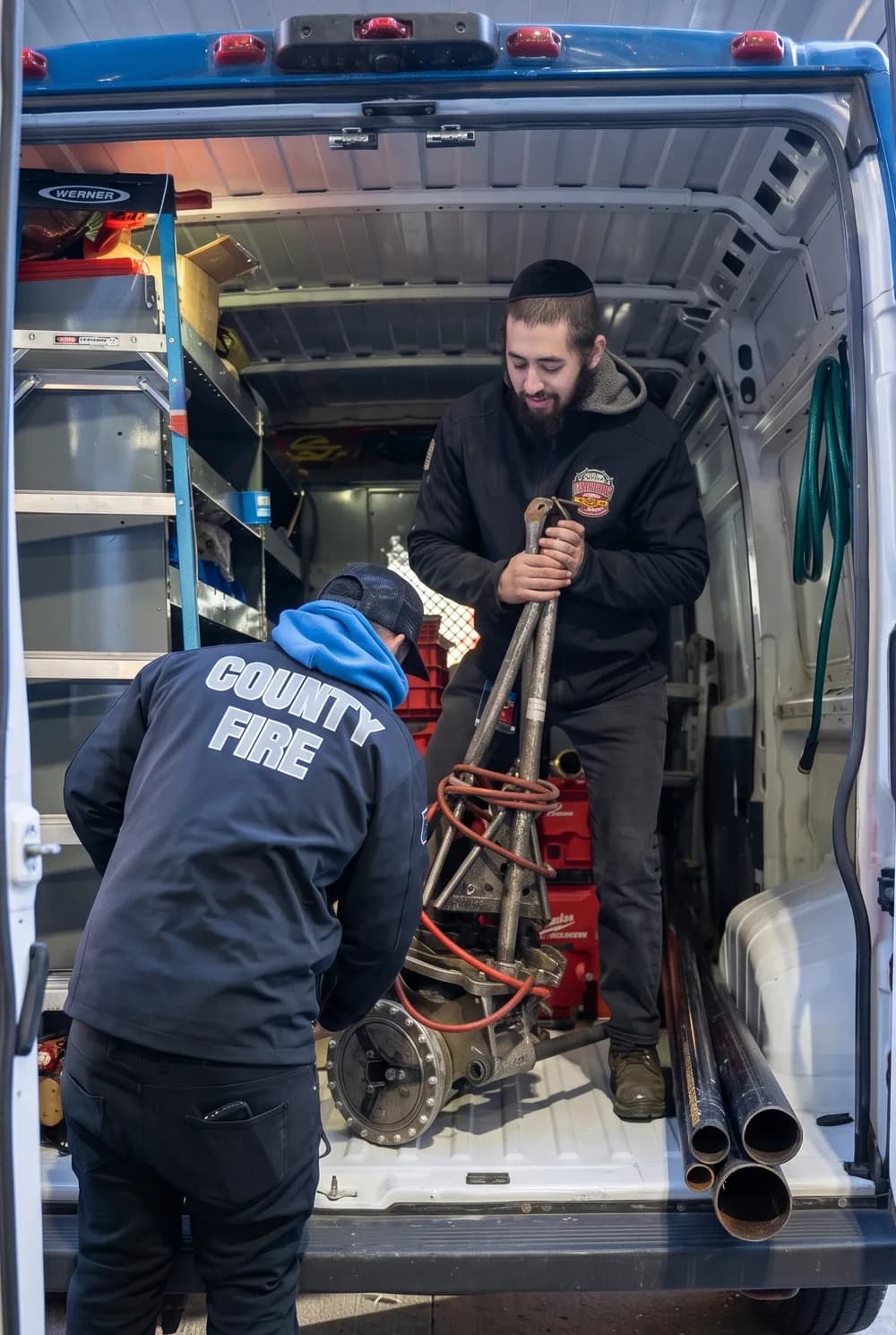 County Fire technicians loading pipe threading equipment from a service van