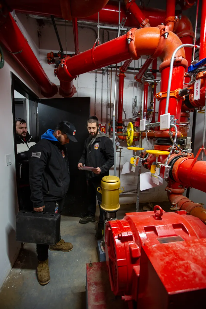 County Fire technicians reviewing fire pump room documentation during a sprinkler installation