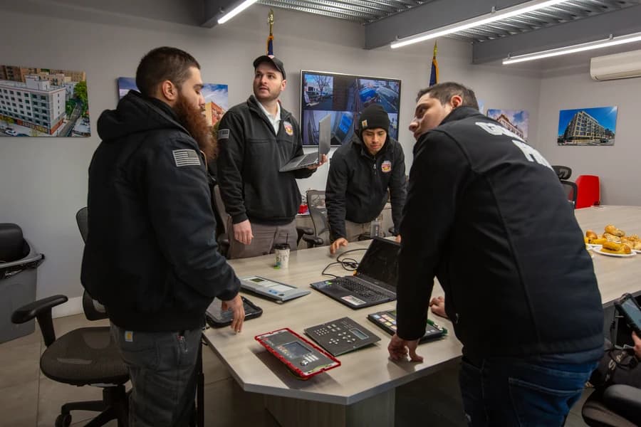 County Fire technicians reviewing fire alarm panels together during a morning team briefing